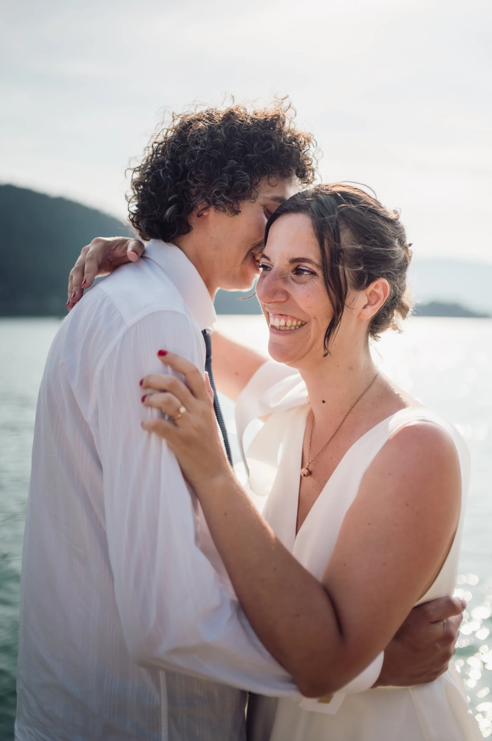 Fanny and Thomas embracing by Lake Annecy after their ceremony