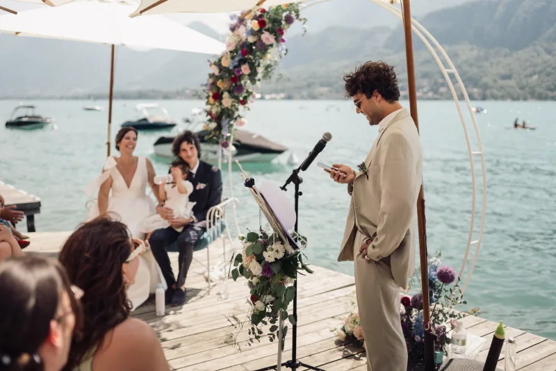 A guest gives a speech during a wedding ceremony beside the lake