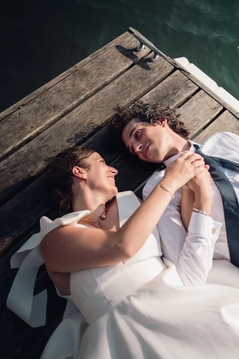 Fanny and Thomas lying on a jetty by Lake Annecy