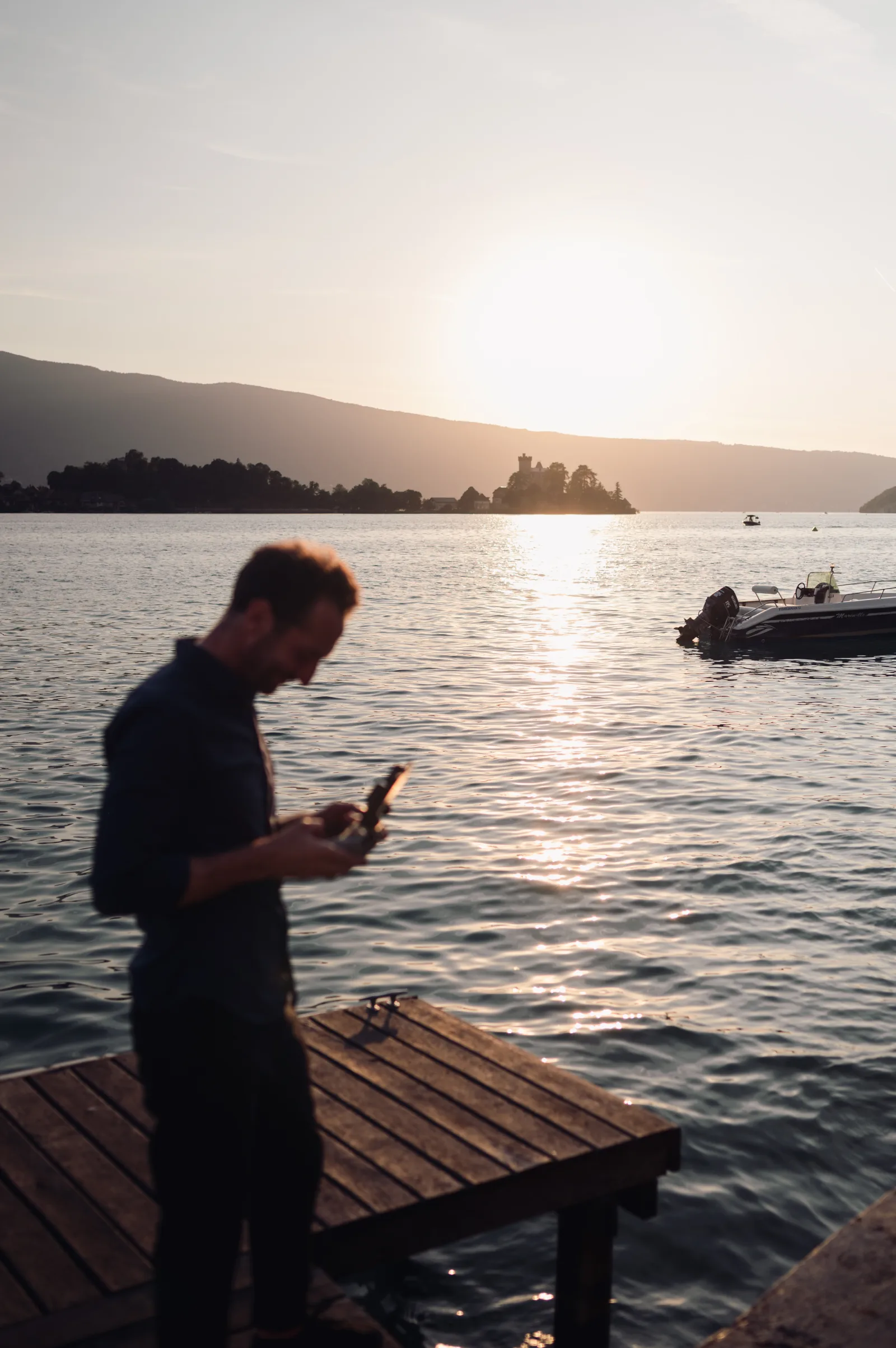 Laurent Henry prepares his equipment at sunset beside Lake Annecy