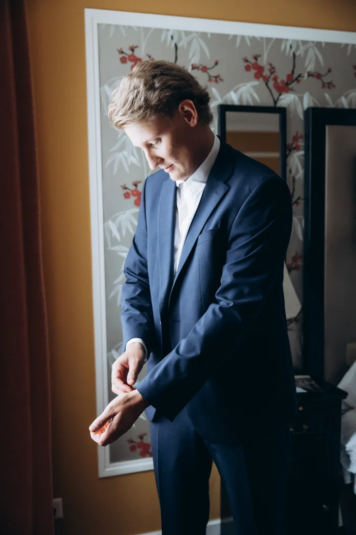 Axel adjusting his navy suit at Hotel Rotary