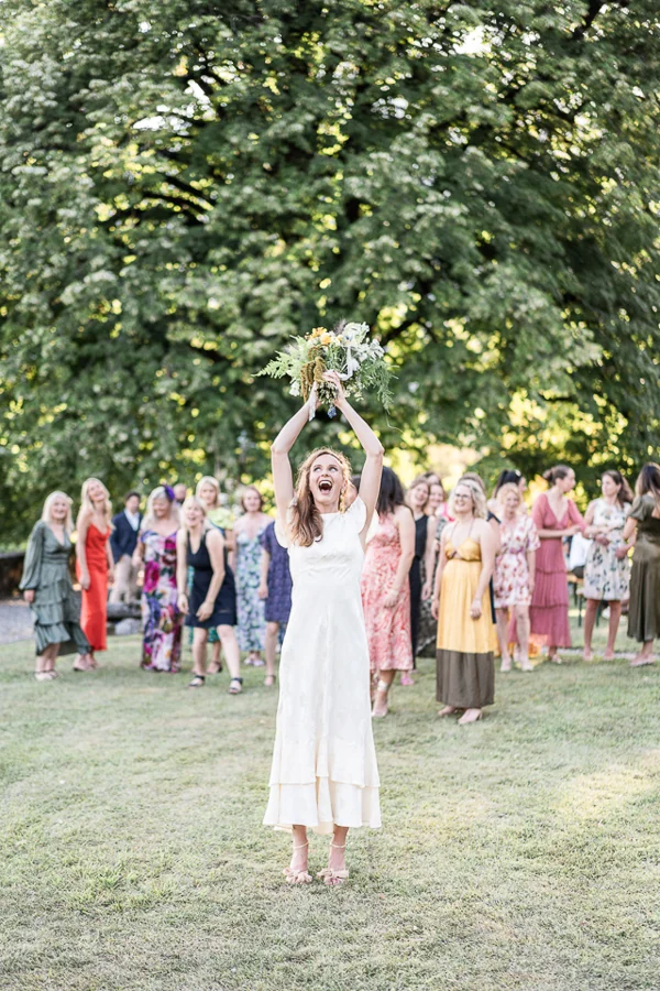 A bride throwing her bouquet in a garden, photographed by Anna Ivanova