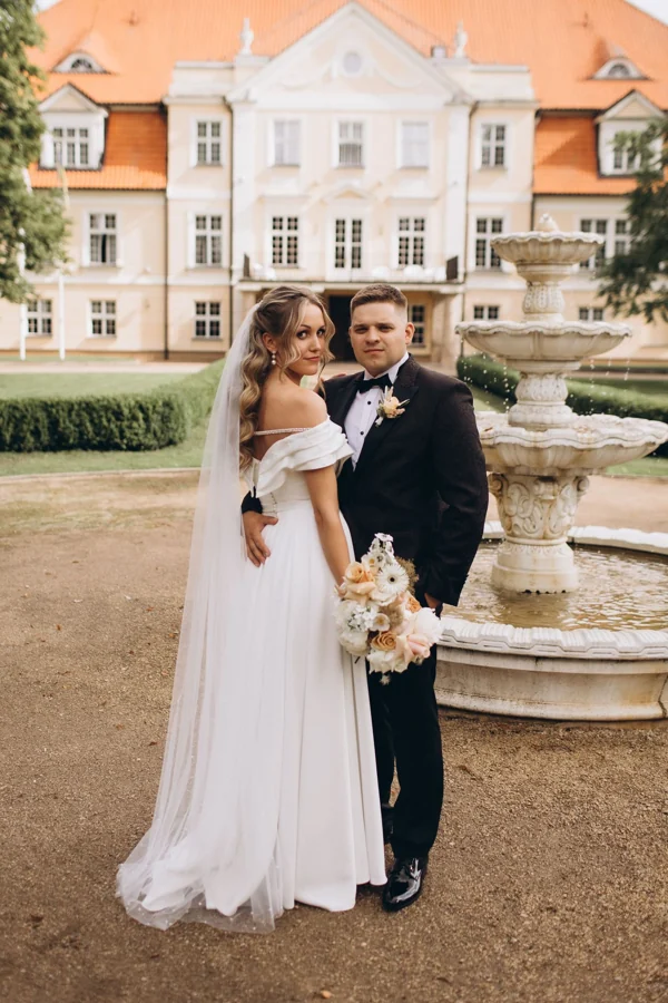 A wedding couple outside a historic house, photographed by Baïba